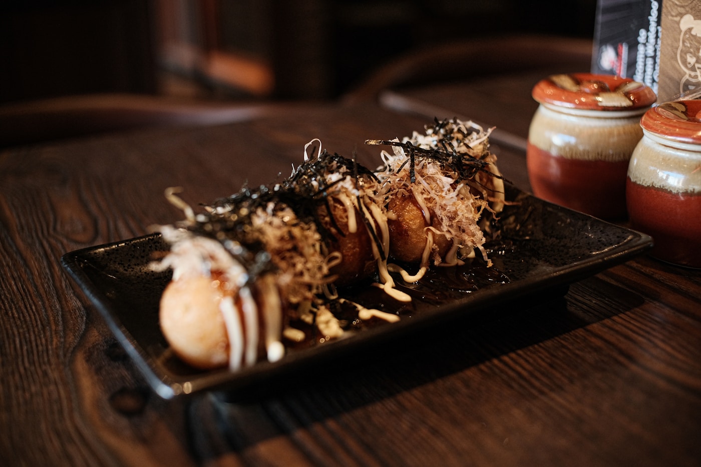A plate of takoyaki finished with sauce and toppings